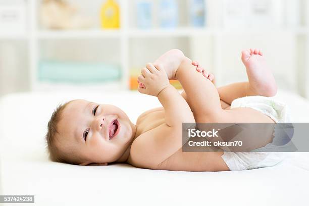 Baby Liegend Weißen Bett Und Halte Die Beine Stockfoto und mehr Bilder von Baby - Baby, Windel, Lächeln