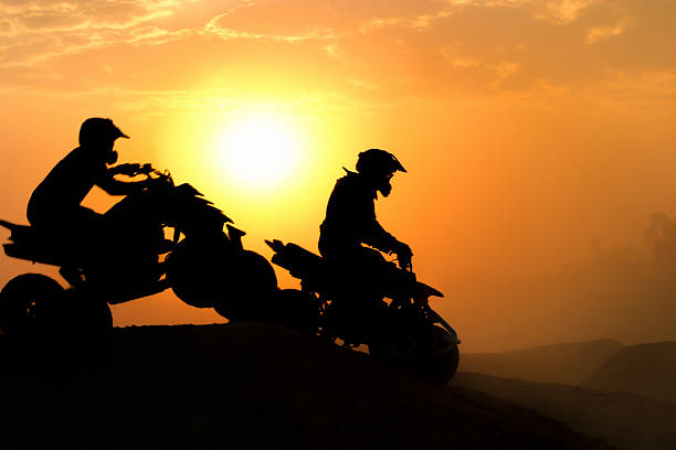 silhouette de sauter en quad ou quad vélos dans le coucher du soleil. - off road vehicle quadbike desert dirt road photos et images de collection