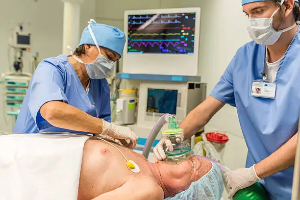Anesthesiologist using oxygen mask on patient in operating theatre.