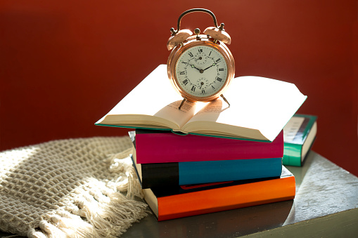 Bedtime reading, alarm clock and books on bedside table
