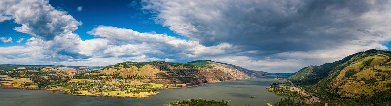 Sweeping panoramic vista over the Columbia River Gorge, from the Oregon shore, railway and highway across the wide Columbia River to the pretty town of Lyle and the Washington hills and forests beyond, Pacific Northwest, USA. ProPhoto RGB profile for maximum color fidelity and gamut.