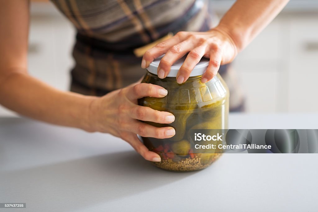 closeup on young housewife opening jar of pickled cucumbers Closeup on young housewife opening jar of pickled cucumbers Jar Stock Photo