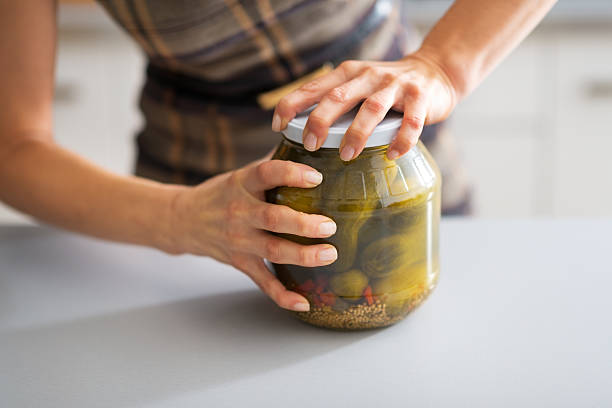 closeup on young housewife opening jar of pickled cucumbers Closeup on young housewife opening jar of pickled cucumbers jar stock pictures, royalty-free photos & images