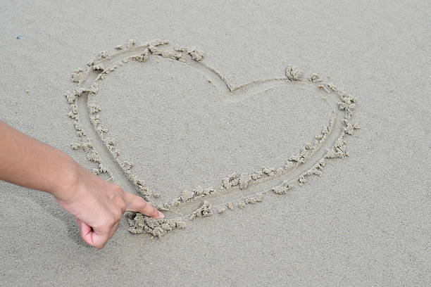 istock heart drawn in the sand on the beach 537437816