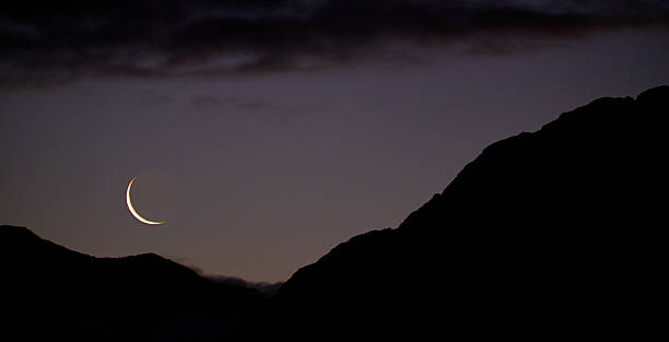 New Moon Over The Southern Alps The sun has set on the Southern Alps in the Arthur's Pass National Park, on New Zealand's South Island. A new moon appears as the thinnest crescent, contrasting with the silhouetted mass of the mountains. crescent photos stock pictures, royalty-free photos & images