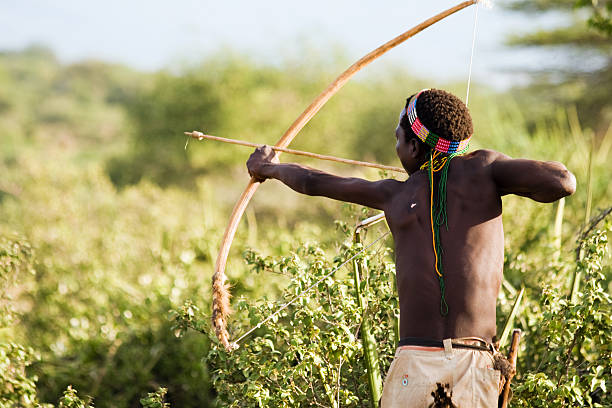 Bushman Hadzabe Lake Eyasi, Tanzania - February 18, 2013: Hazabe bushman with bow and arrow during hunting in the bush. Hazabe tribe threatened by extinction. bushmen stock pictures, royalty-free photos & images