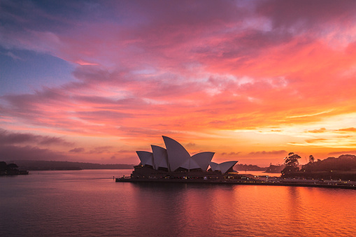 Sydney Australia - November 23, 2014: The iconic form of Sydney Opera House is silhouetted against a dramatic early morning sky.