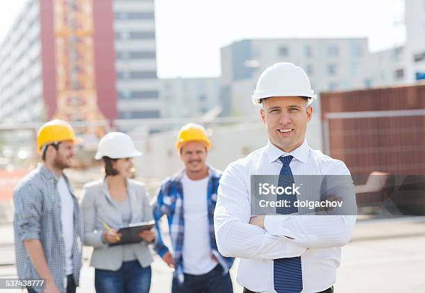 Group Of Smiling Builders In Hardhats Outdoors Stock Photo - Download Image Now - 2015, Adult, Architect