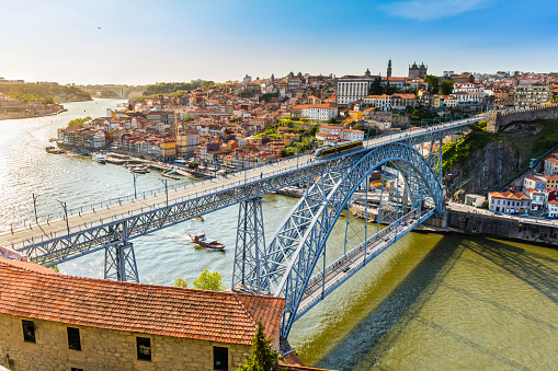 Metro rail seen travelling accross the Dom Luis I bridge that lies over river Douro in Porto city. This is a popular tourist destination and declared a UNESCO world heritage site. The cityscape seen on above and below the bridge.