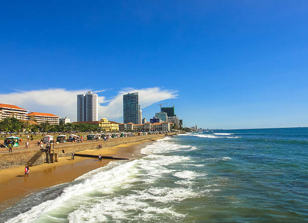 Stock photo showing aerial view of metal railway the line and gravel of southern line diesel railroad track in Colombo, Sri Lanka running parallel to the coast with waves breaking on the rocky shore.