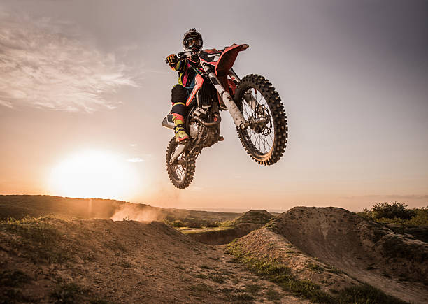 motociclista di motocross salto in alto di esecuzione al tramonto. - motorcycle racing foto e immagini stock