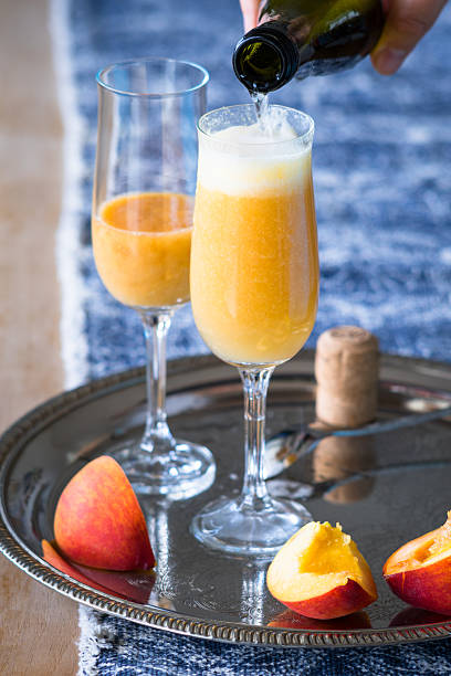istock Pouring Prosecco wine to pureed peach to make Bellini cocktail 537446054
