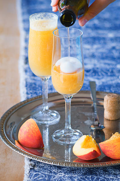 istock Pouring Prosecco wine to pureed peach to make Bellini cocktail 537446100