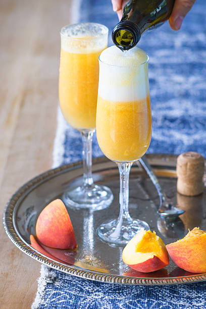 istock Pouring Prosecco wine to pureed peach to make Bellini cocktail 537446152