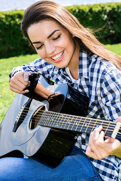 istock girl on a green meadow playing guitar 537448164