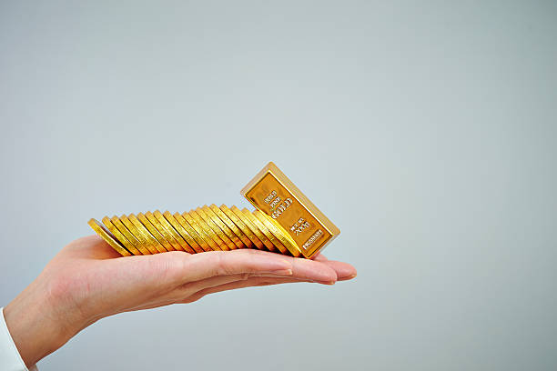 Coins and gold bar on hand stock photo