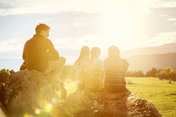 Photo of Friends relaxing on rock at field