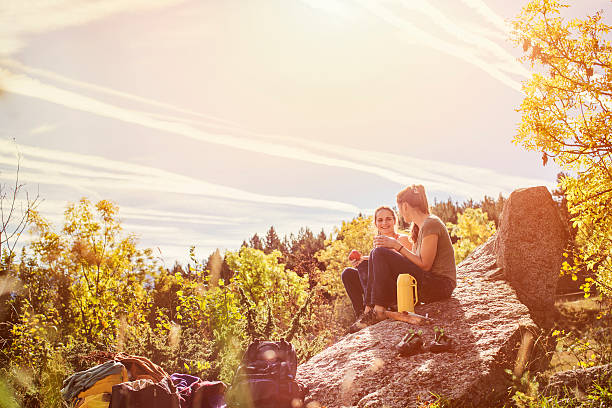 hiking female friends having snacks on rock - food mountain стоковые фото и изображения