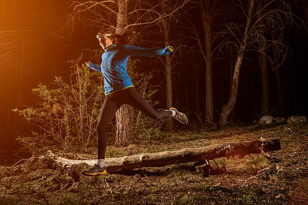 female jogger running in forest at night - night running imagens e fotografias de stock