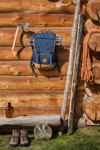 Backpack and axe hanging outside log cabin