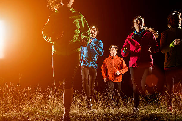 joggers running on field at night - night running imagens e fotografias de stock