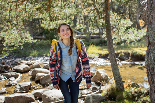 Happy young female hiker walking in forest