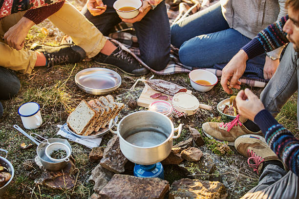 friends preparing breakfast at campsite - food mountain стоковые фото и изображения