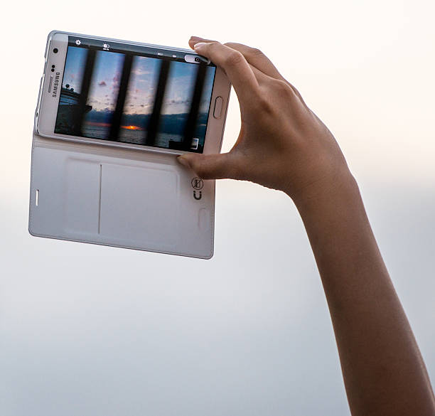 Key West, USA  - January 8, 2015: Hand Holding Samsung mobile phone photographing sunset
