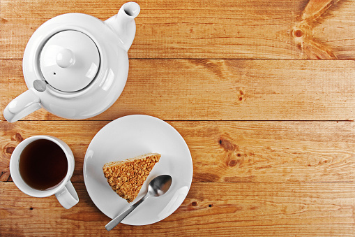 piece of cake and tea pot on wooden table