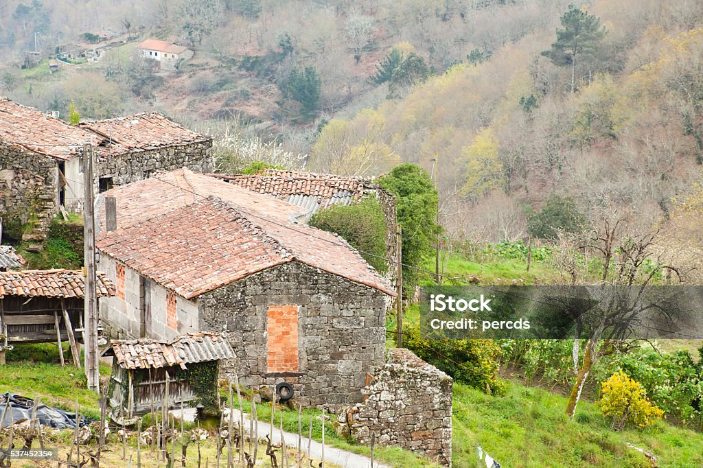 Small old village in a rural area, Galicia, Spain. View from above of an old small village in a rural area,mountainous countryside in Galicia, Spain. Forest and meadows in winter time. Agricultural Field Stock Photo