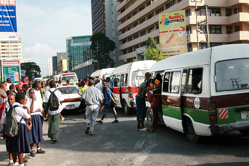 Dar es Salaam, Tanzania - February 21, 2008: Rush hour in the city center, traffic congestion, passenger vans blocked the street, people standing on bus stop waiting for a municipal bus.