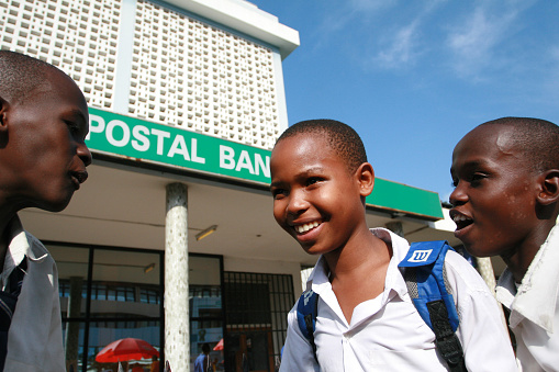 Dar es Salaam, Tanzania - February 21, 2008: Three black African boys older students, chatting in the street, in the city center.