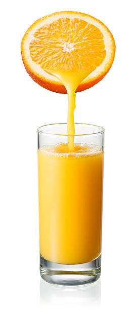 Orange juice is pouring into the glass. Isolated on white