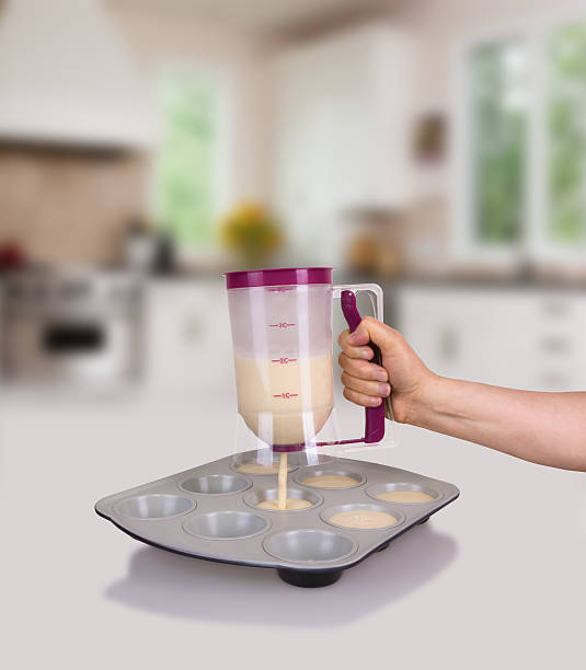 Woman is making muffin with batter dispenser stock photo