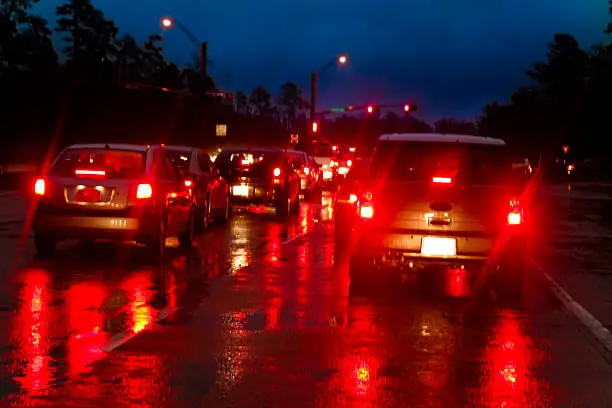 Photo of City street. Rainy night, road. Vehicles, tail lights. Wet. Cars.