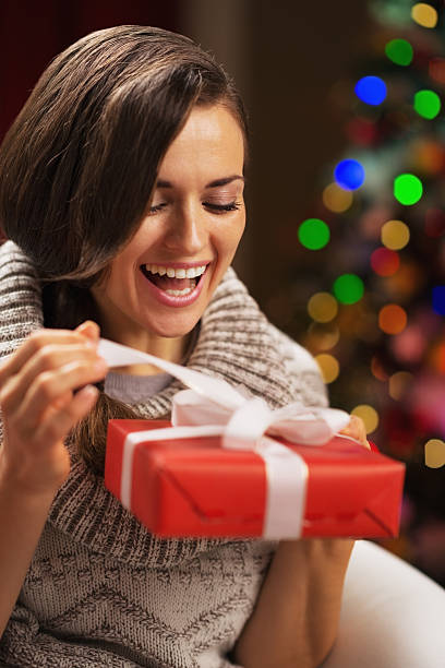 istock Happy woman opening present box in front of christmas lights 537458006