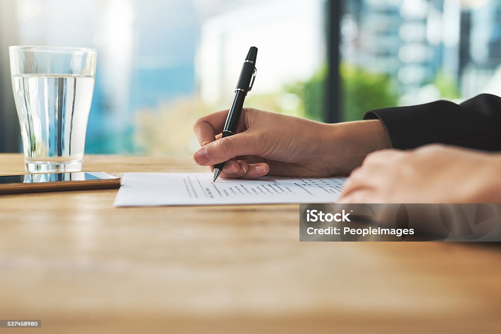 Browsing over some documents Shot of a woman filling in some paperwork Form - Document Stock Photo