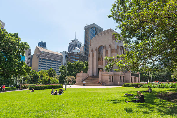 Sydney, Australia - November 10, 2015: People sitting on the turf, taking a  noon break in the Hyde Park, the ANZAC War Memorial is in the background.