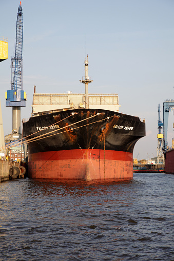 Hamburg, Germany - September 03, 2011: The bulk container freight vessel Falcon Arrow is safely towed to one of Hamburgs large freight docks to be loaded and prepared for its next journey to China. The Falcon Arrow runs under the flag of Bahamas and is 200 meters long and 16 knots fast.