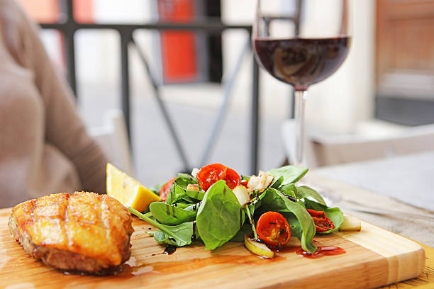 Italian duck breast served with fresh salad and a glass of red wine outdoors at a restaurant in Rome.