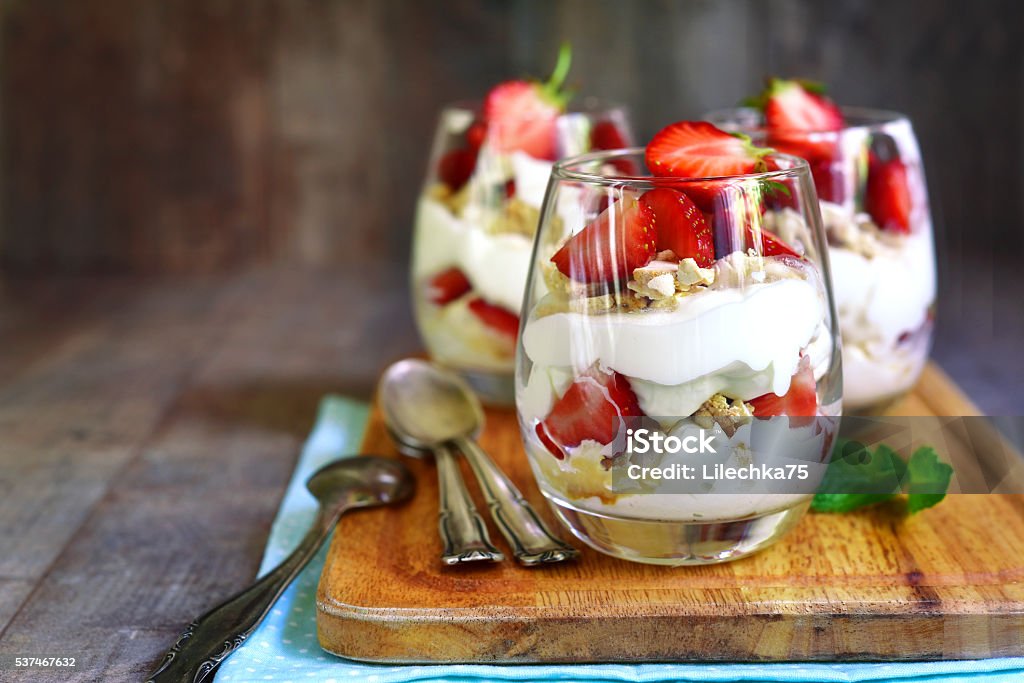 Delisious traditional english dessert eton mess. Delisious traditional english dessert eton mess with strawberry on a wooden background. Strawberry Stock Photo