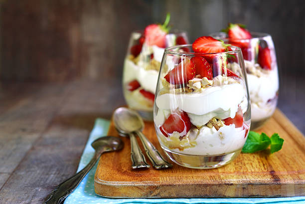 Delisious traditional english dessert eton mess. Delisious traditional english dessert eton mess with strawberry on a wooden background. parfait stock pictures, royalty-free photos & images