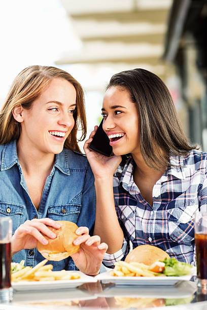 istock Friends Looking At Each Other While Answering Call At Cafe 537467702
