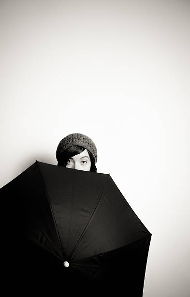 istock Young pretty woman with hat, eyes from behind black umbrella 537468507