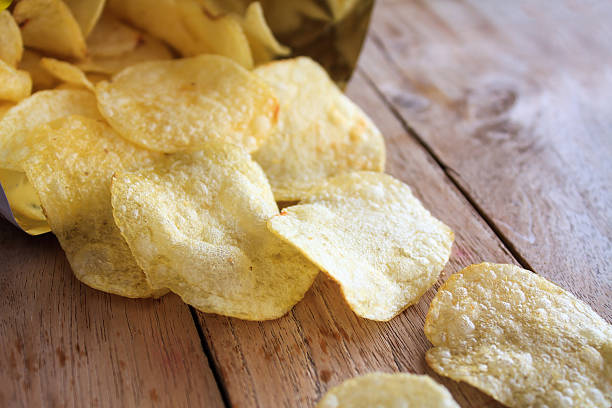 istock Opened pack of delicious potato chips on wood table 537469124