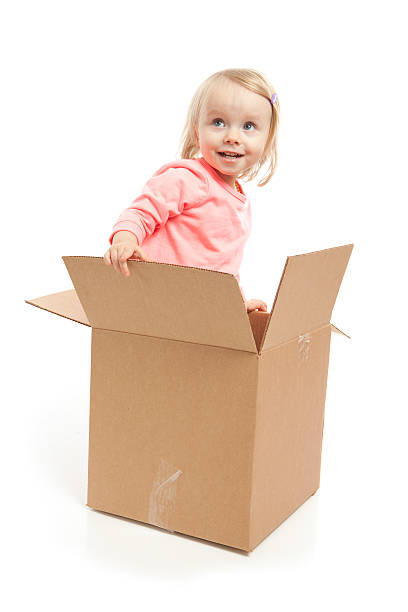 istock Little Girl Playing in Corrugated Box on White Background 537469360