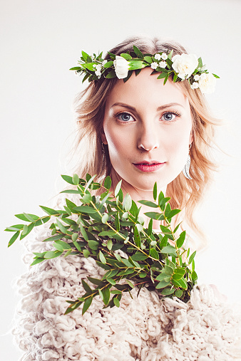 Beautiful young woman with flower wreath in her hair, holding beautiful leaves 