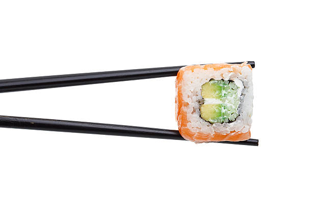 istock Salmon sushi roll in chopsticks isolated on white background 537471290