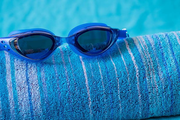 istock Blue swimming goggles on beach towel 537471558