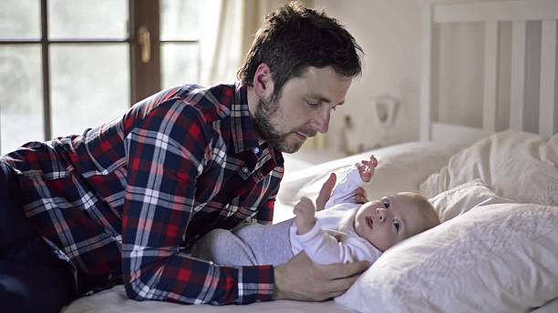 istock Baby boy lying on bed, with his father 537472656